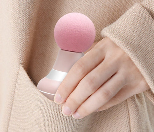 Hand holding the pink mini massager against a forearm in a beige sweater